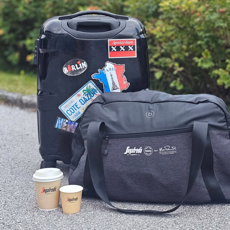 Imagebild kleine Reisetasche und Koffer mit Destinationsaufklebern mit Coffee to go-Bechern