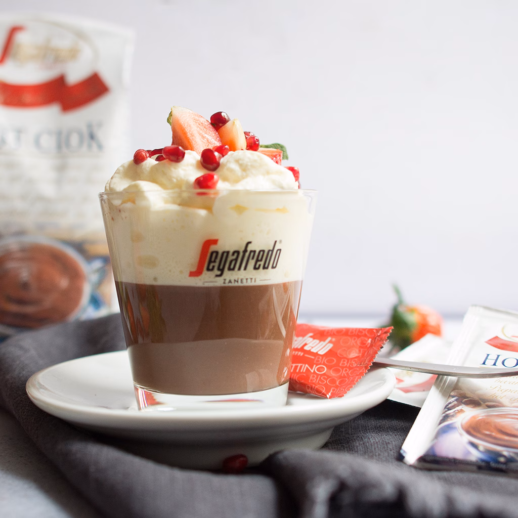 Imagebild Glas mit Schokoladenpudding und Schlagobers garniert mit Früchten, im Hintergrund Produktpackung